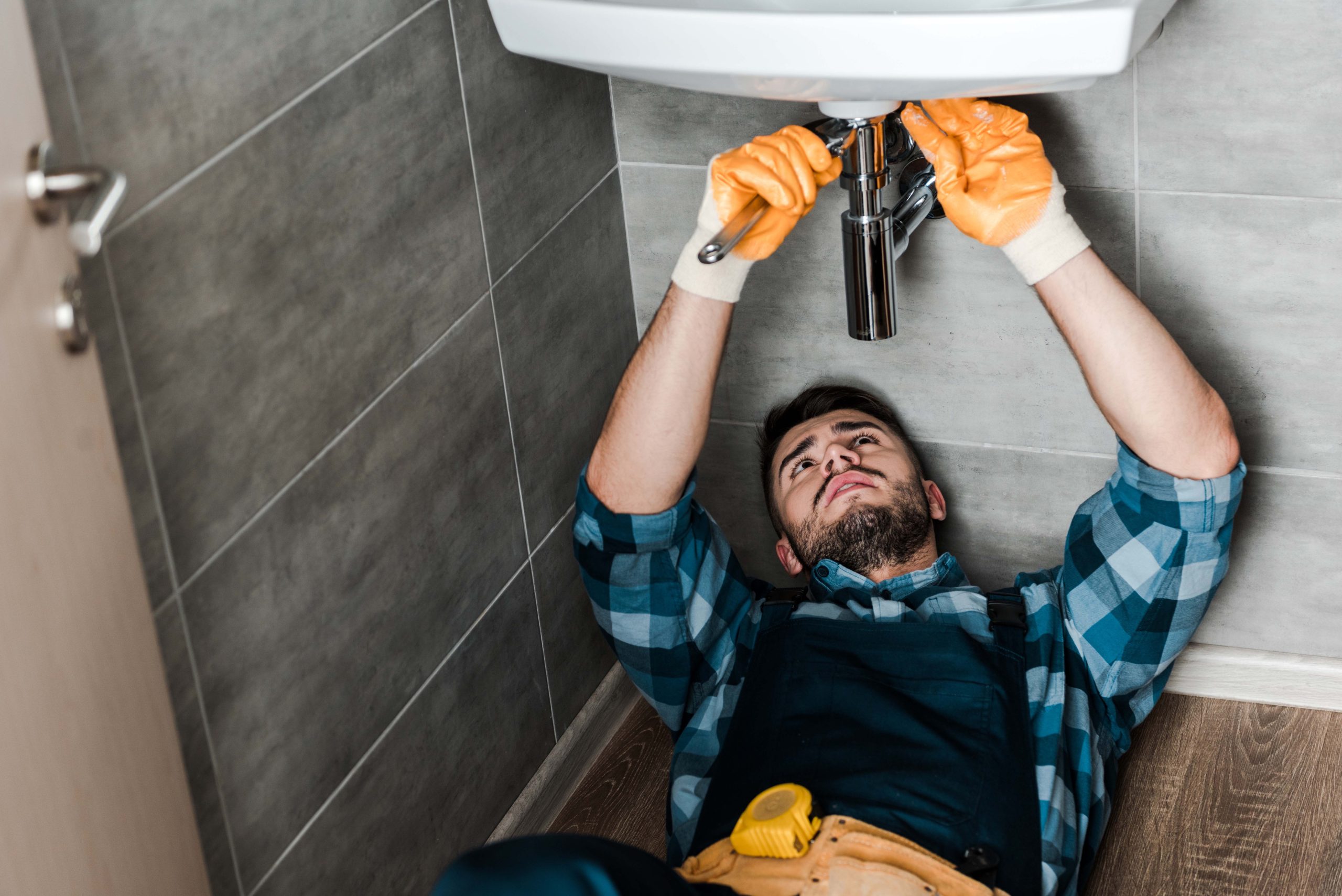 selective focus of repairman fixing water damage with wrench in