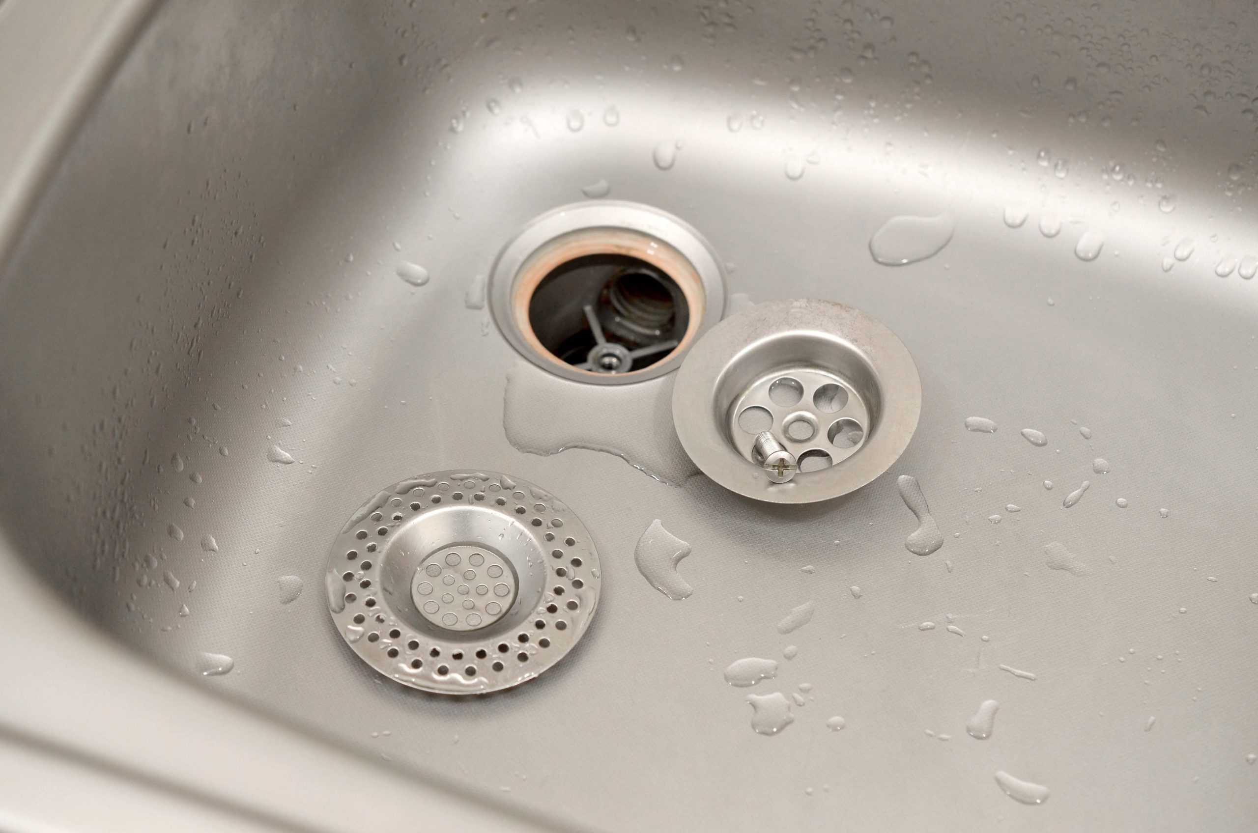 silvery kitchen sink with a disassembled protective filter during the repair process