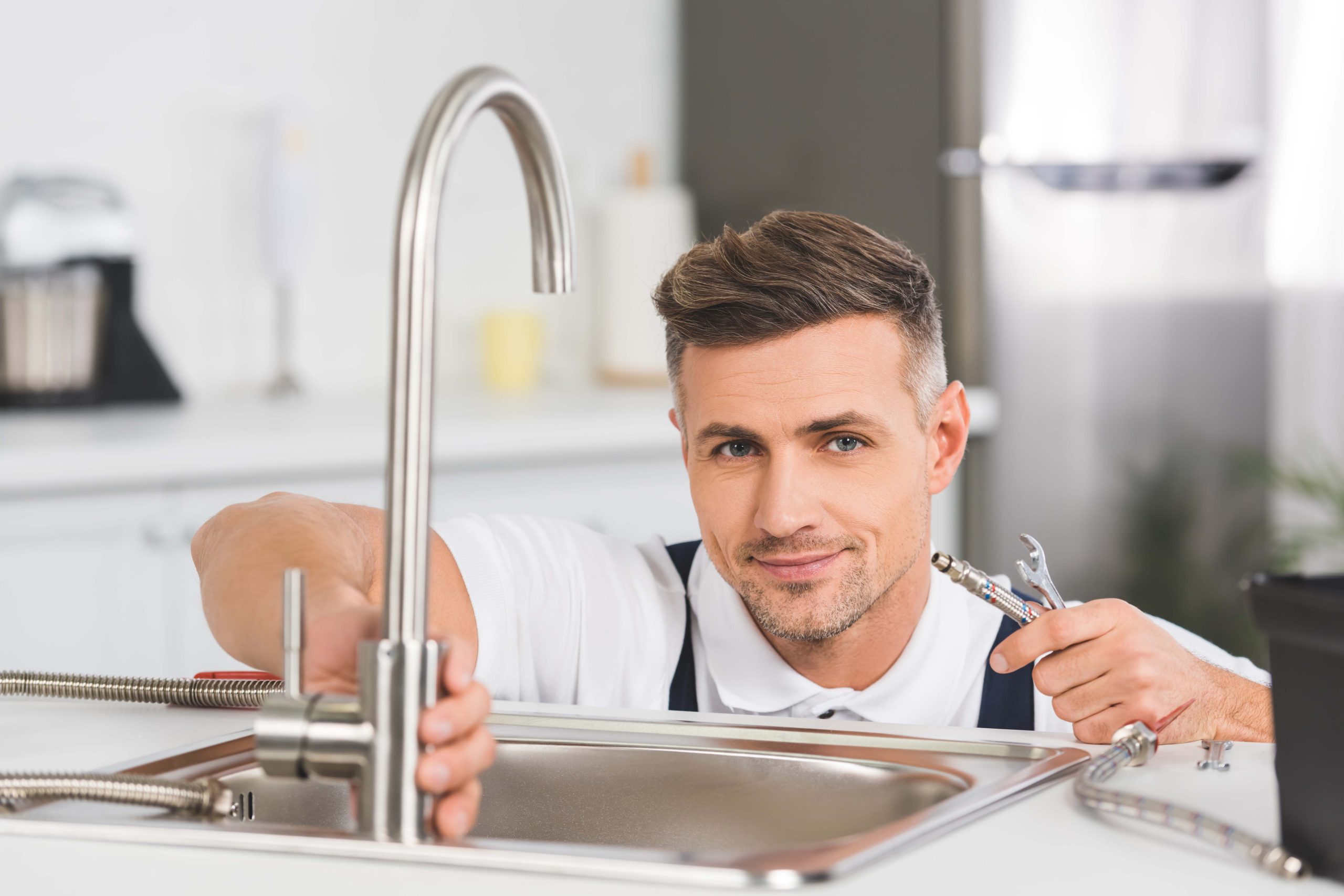 smiling adult repairman holding pipe and spanner while repairing