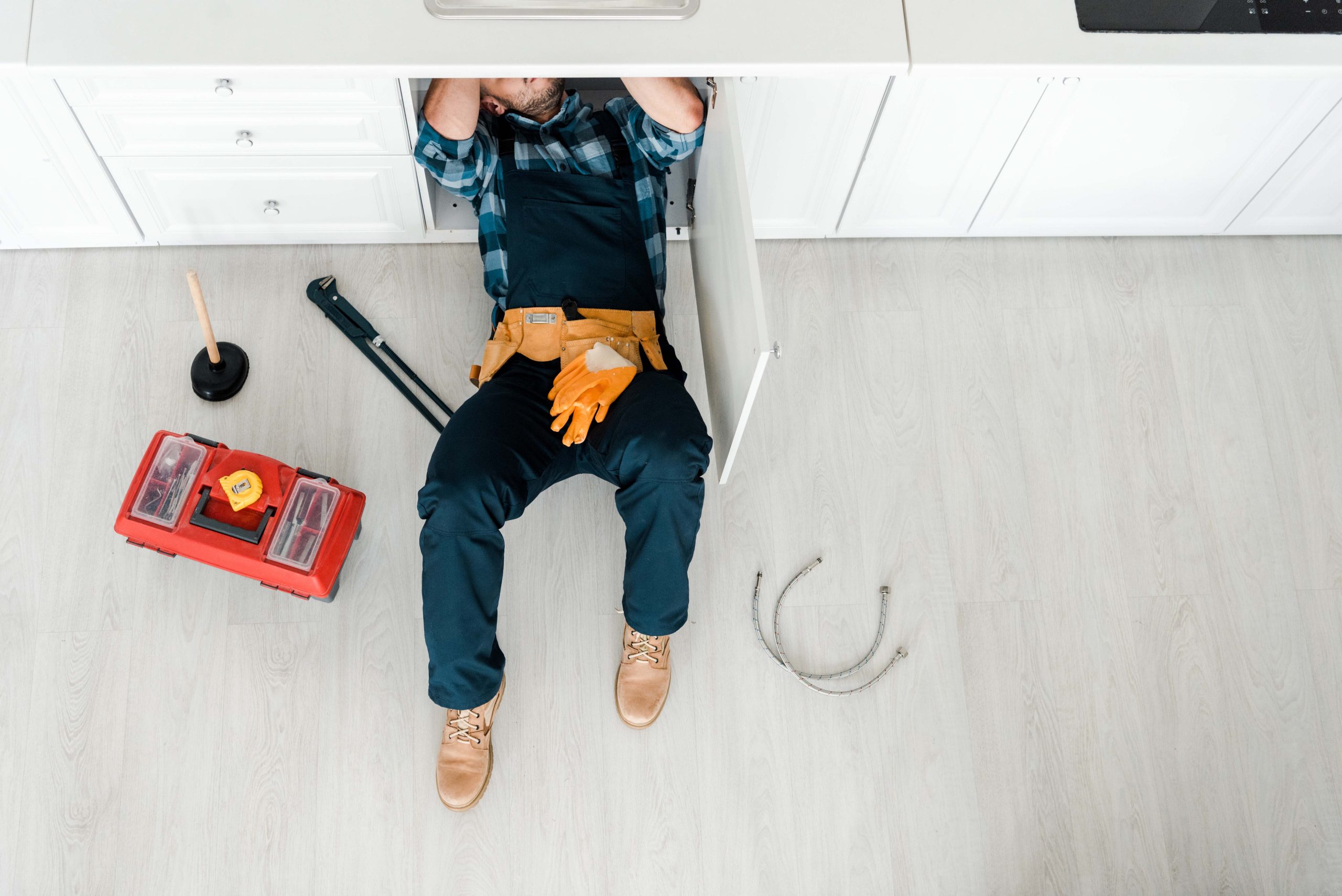 top view of handyman lying on floor near toolbox