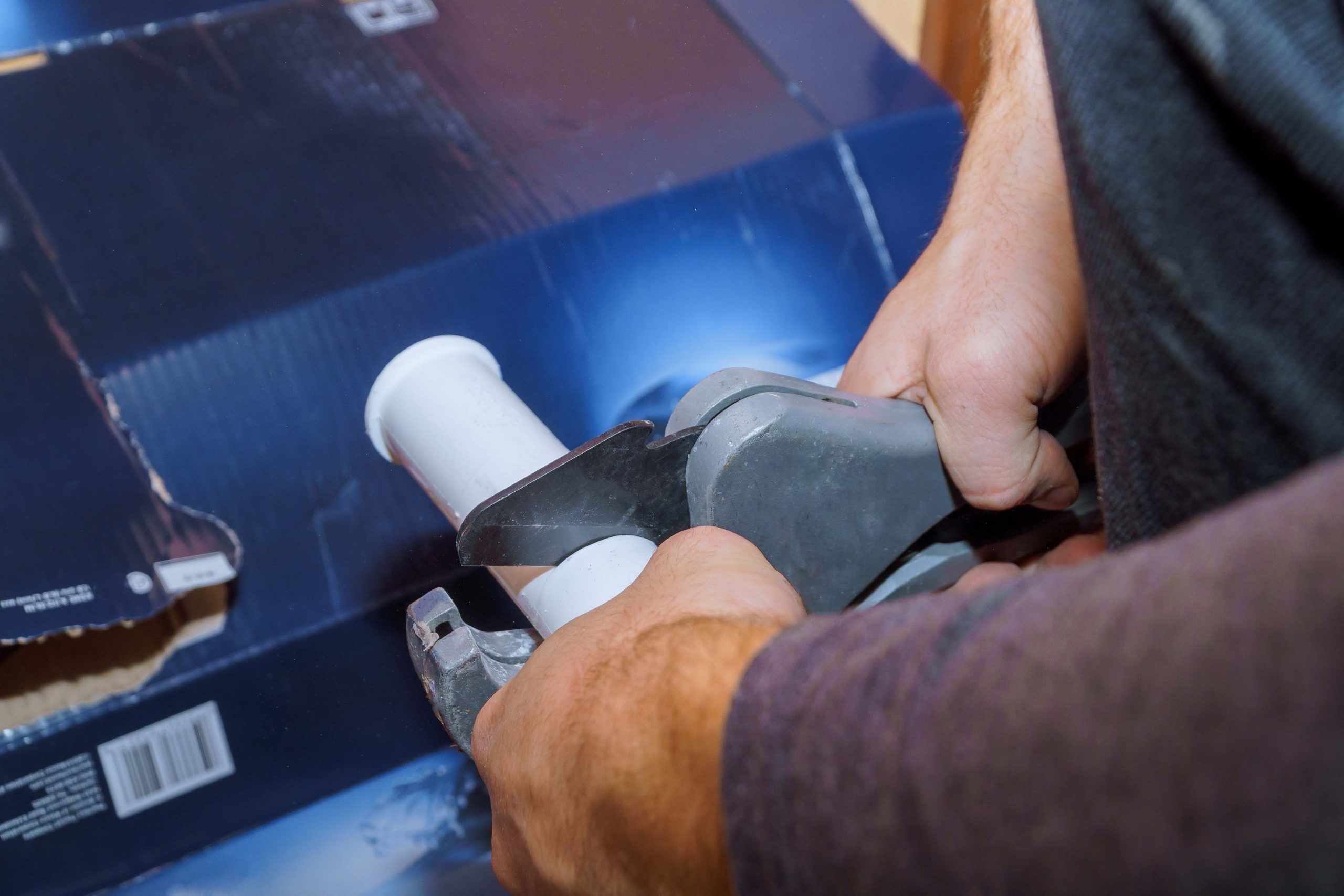 using a cutter for plastic pipes when repairing domestic water pipes, hand plumbing close up.