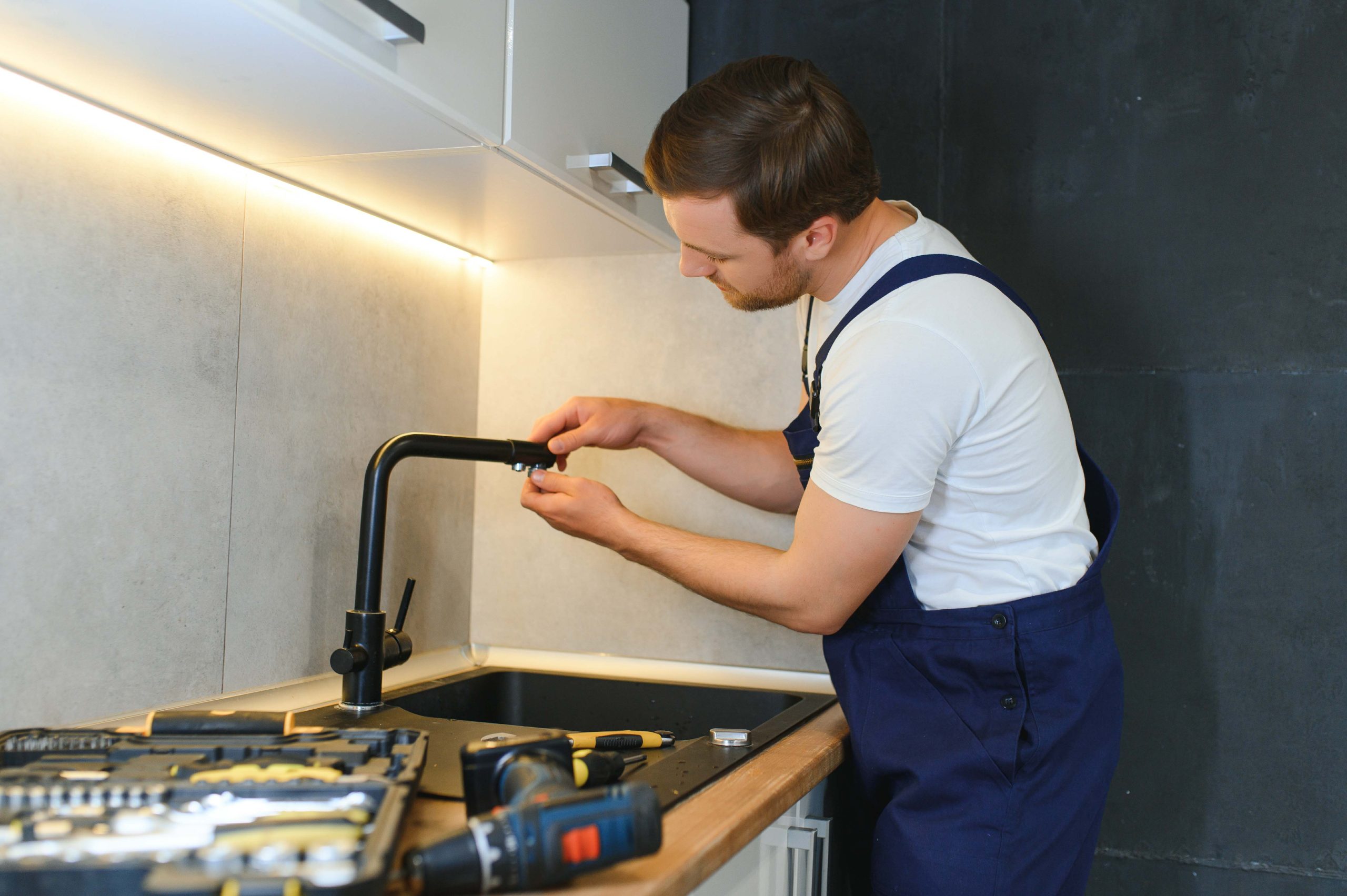 young repairman installing faucet of kitchen sink in kitchen room