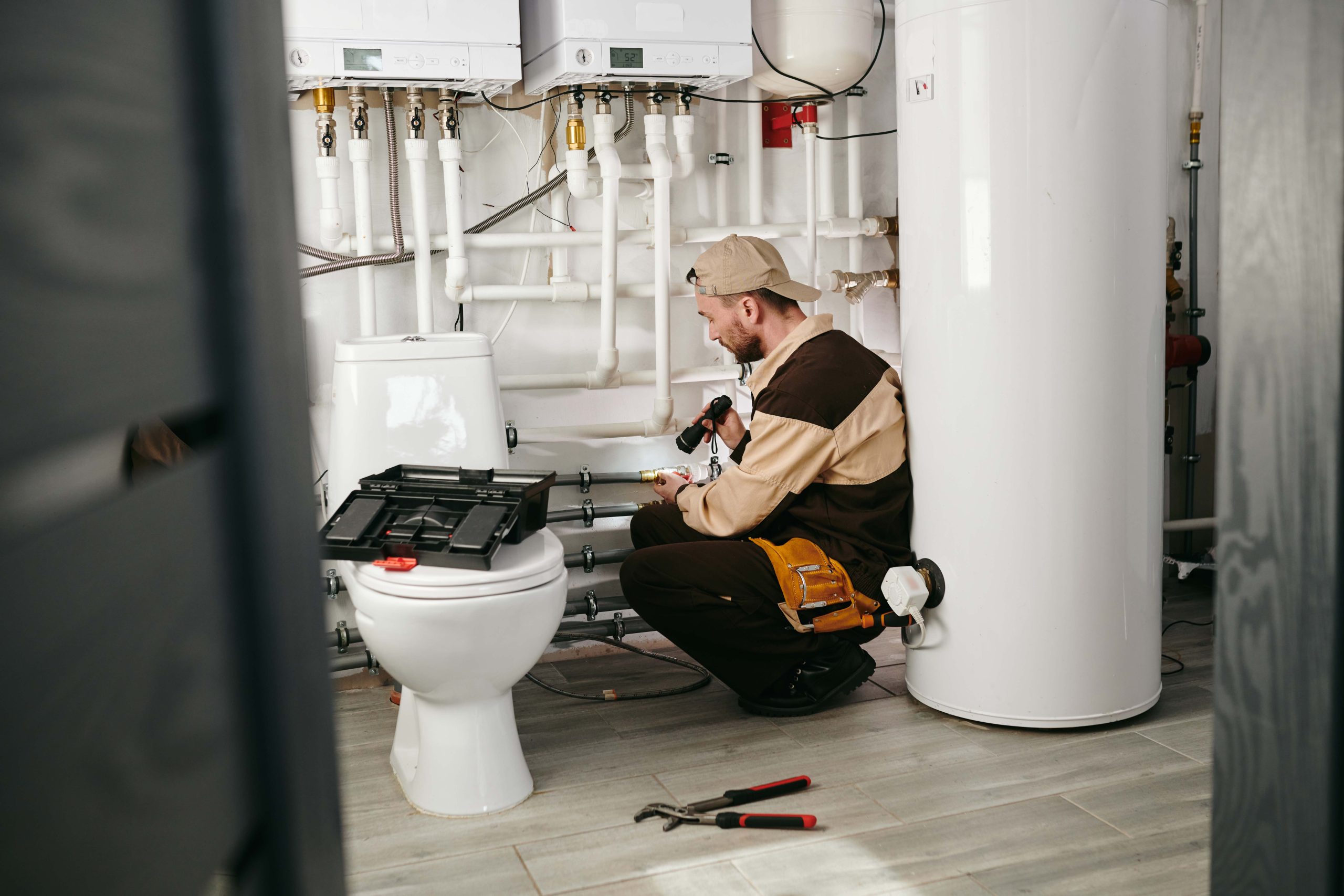 young repairman in uniform examining part of pipe