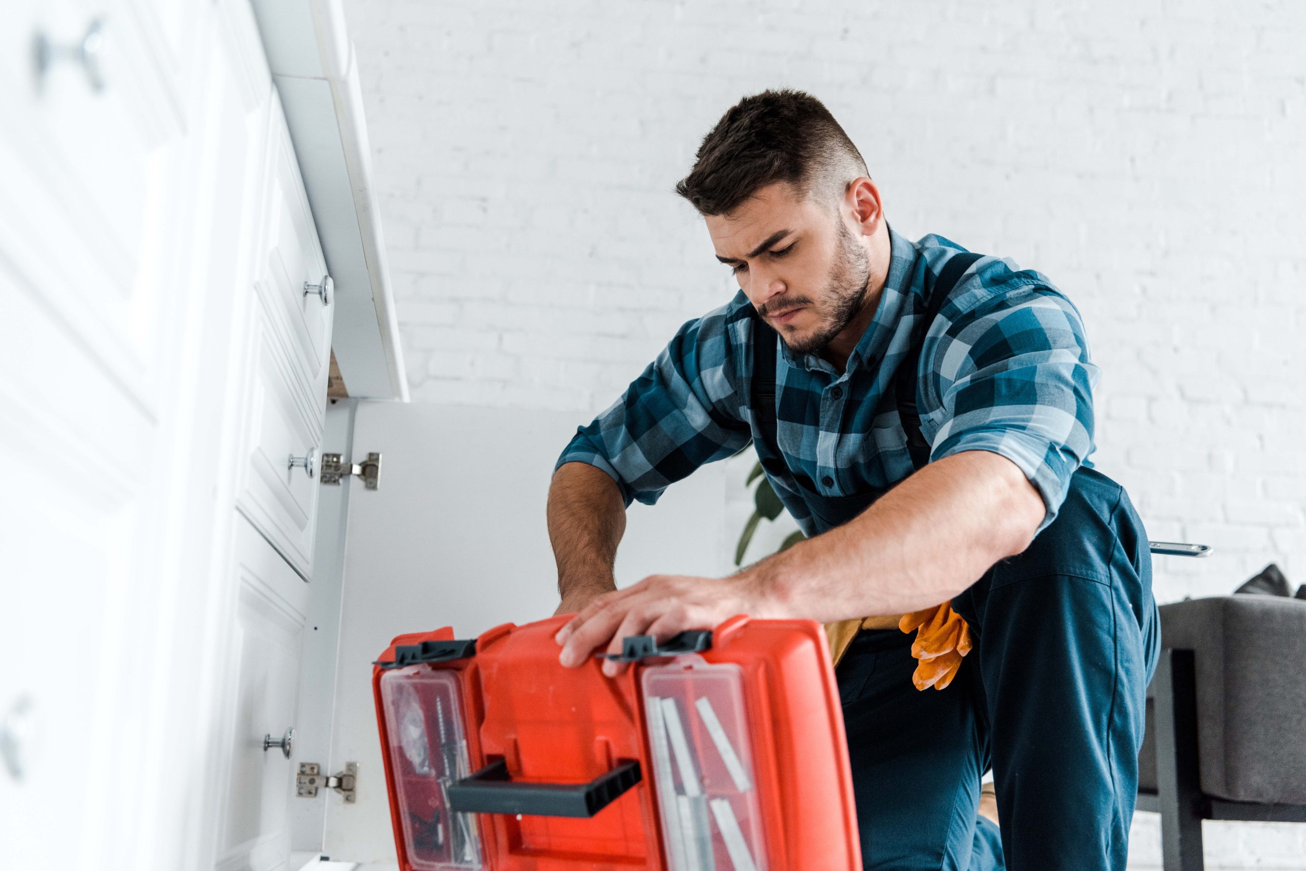 selective focus of handsome handyman looking at opened toolbox i