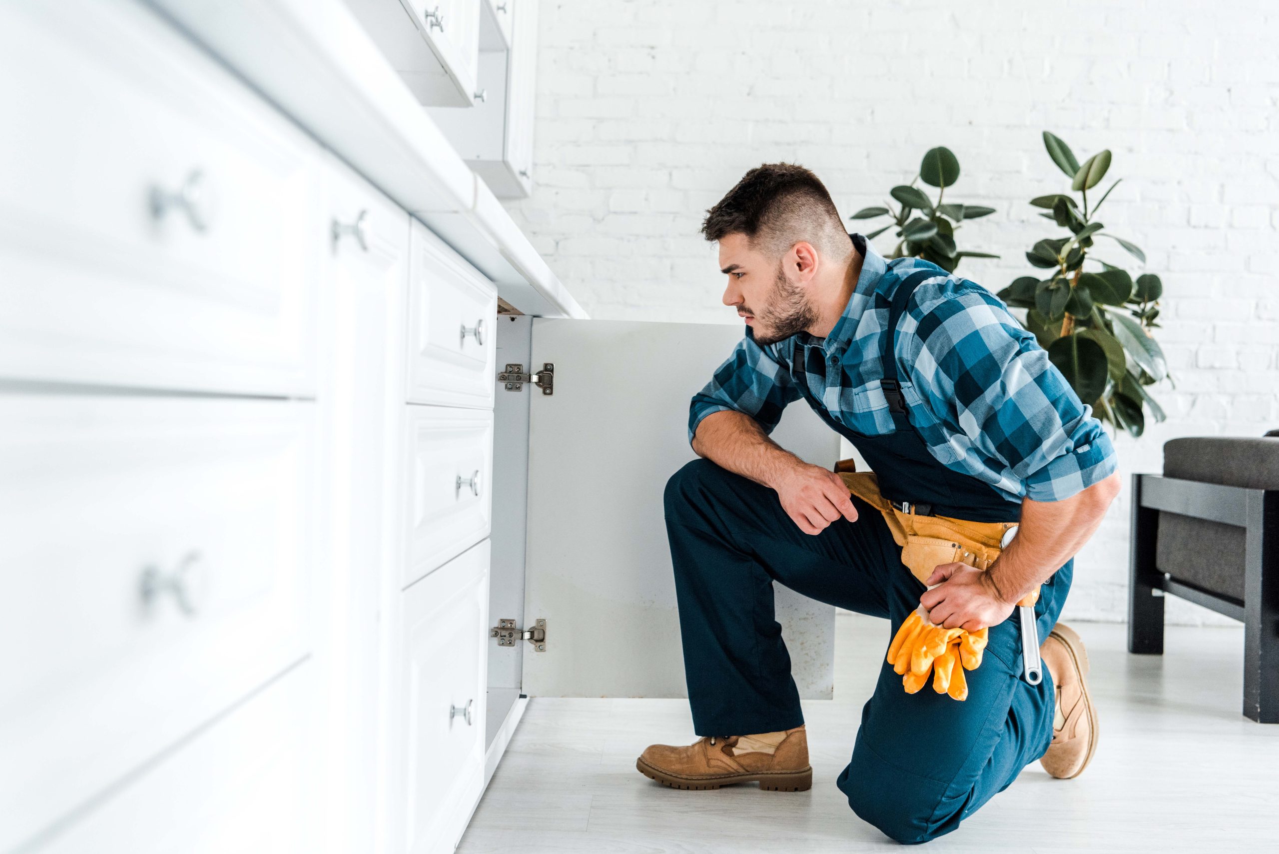 selective focus of handsome handyman with tool belt sitting near